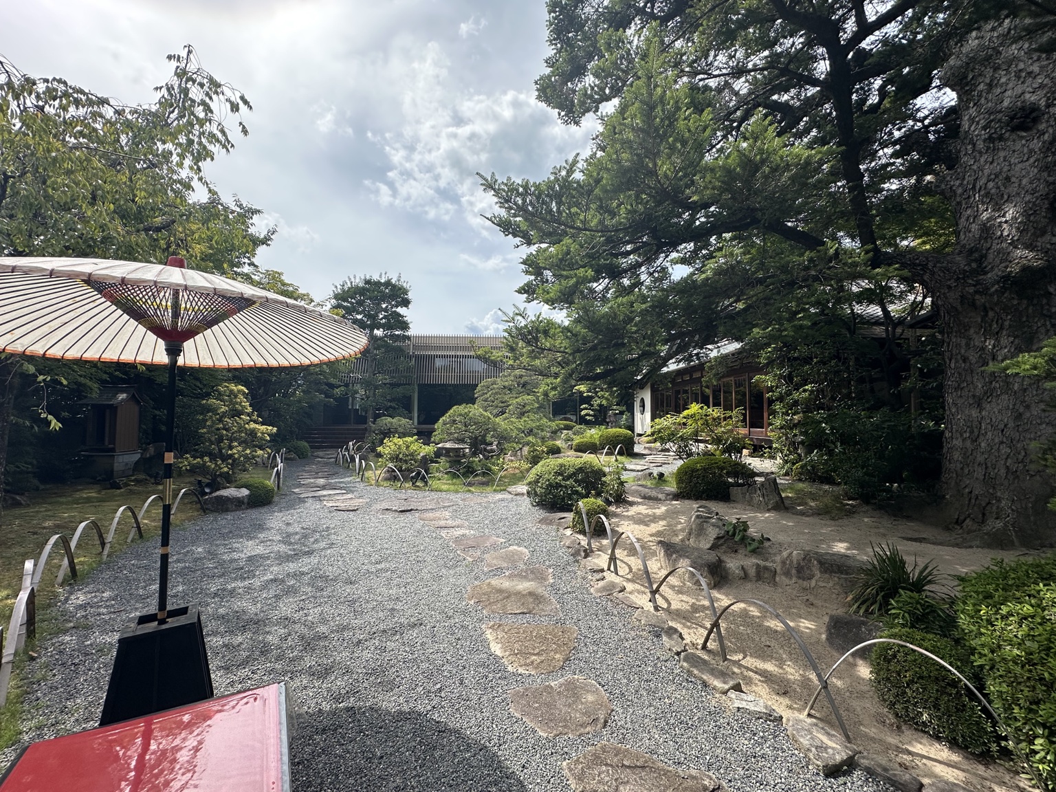 和傘の向こうに広がる三瀧荘の日本庭園
