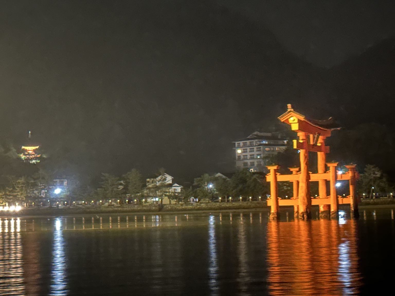 夜の嚴島神社の大鳥居と水面に映る光